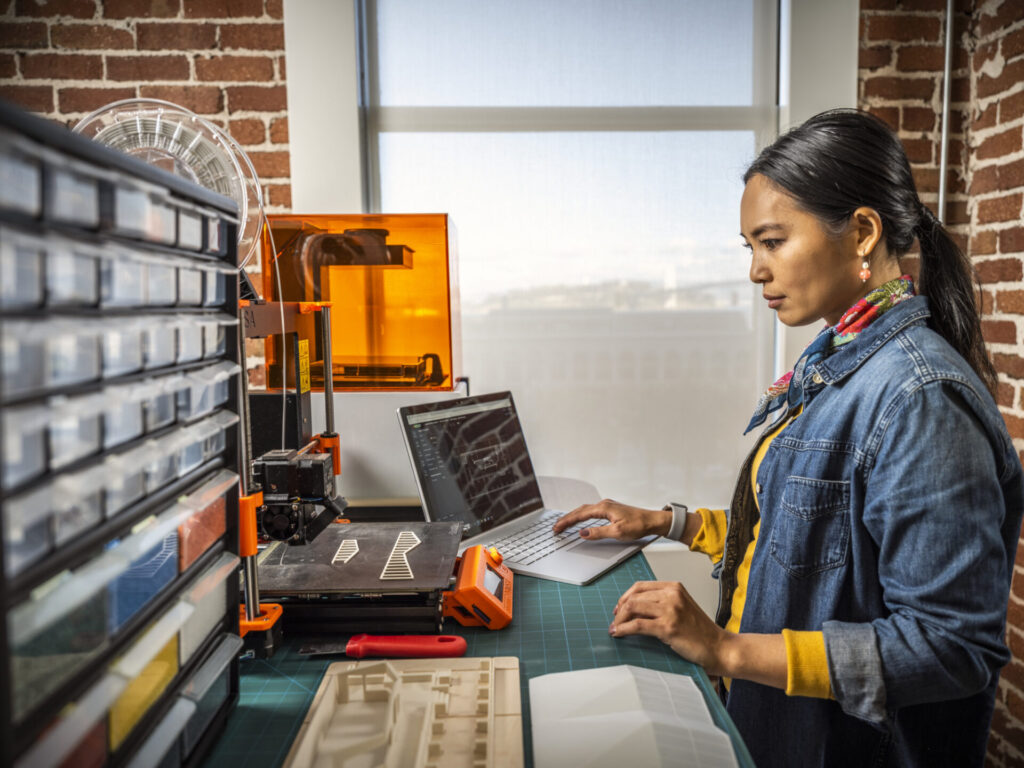 Woman using AutoCAD in a maker space environment.
