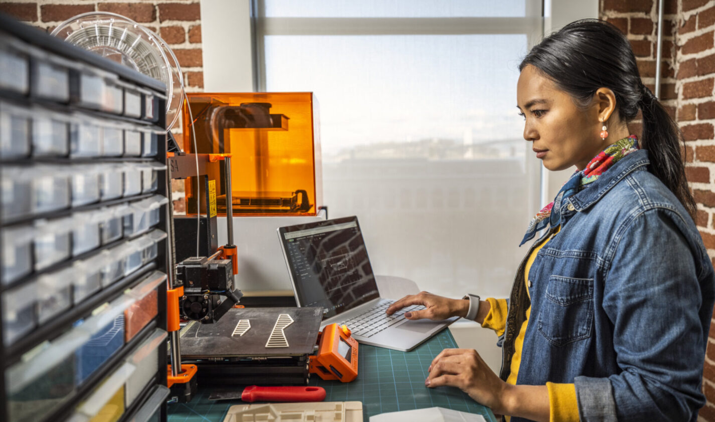 Woman using AutoCAD in a maker space environment.